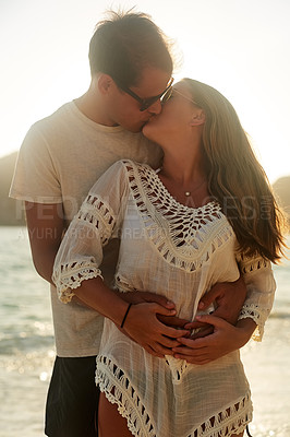 Buy stock photo Shot of an affectionate young couple on the beach at sunset