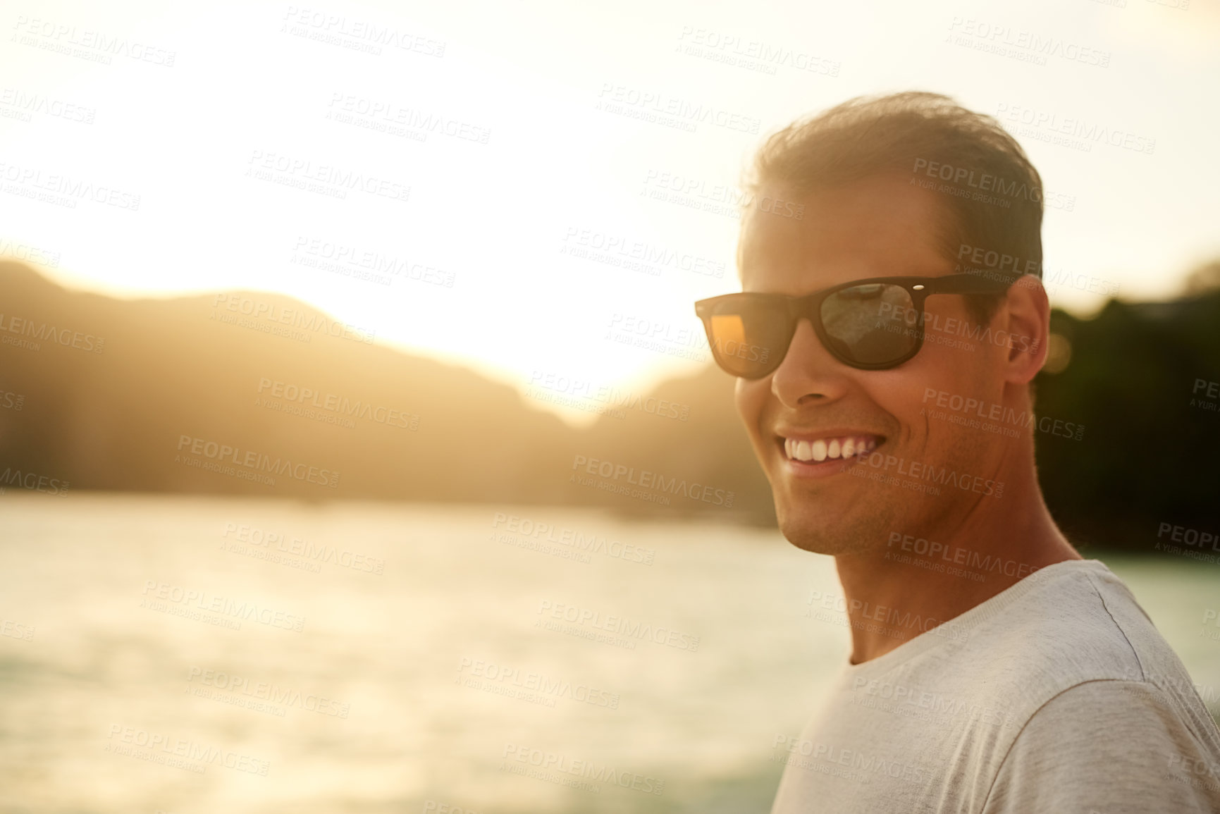Buy stock photo Portrait of a handsome young man standing on the beach at sunset