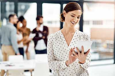Buy stock photo Shot of a businesswoman using a tablet with her colleagues in the background