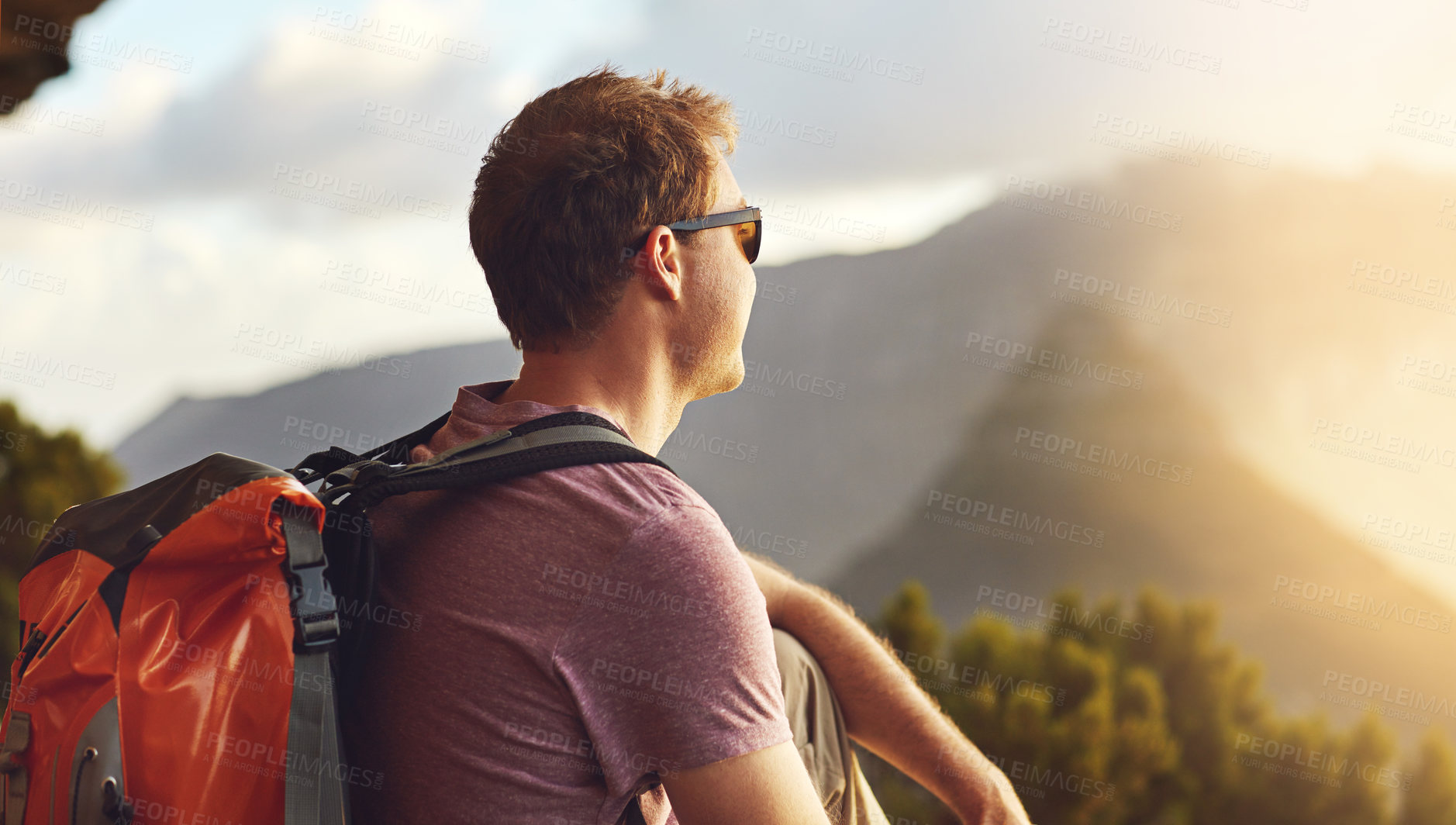 Buy stock photo Shot of a young man admiring the view from the top of a mountain