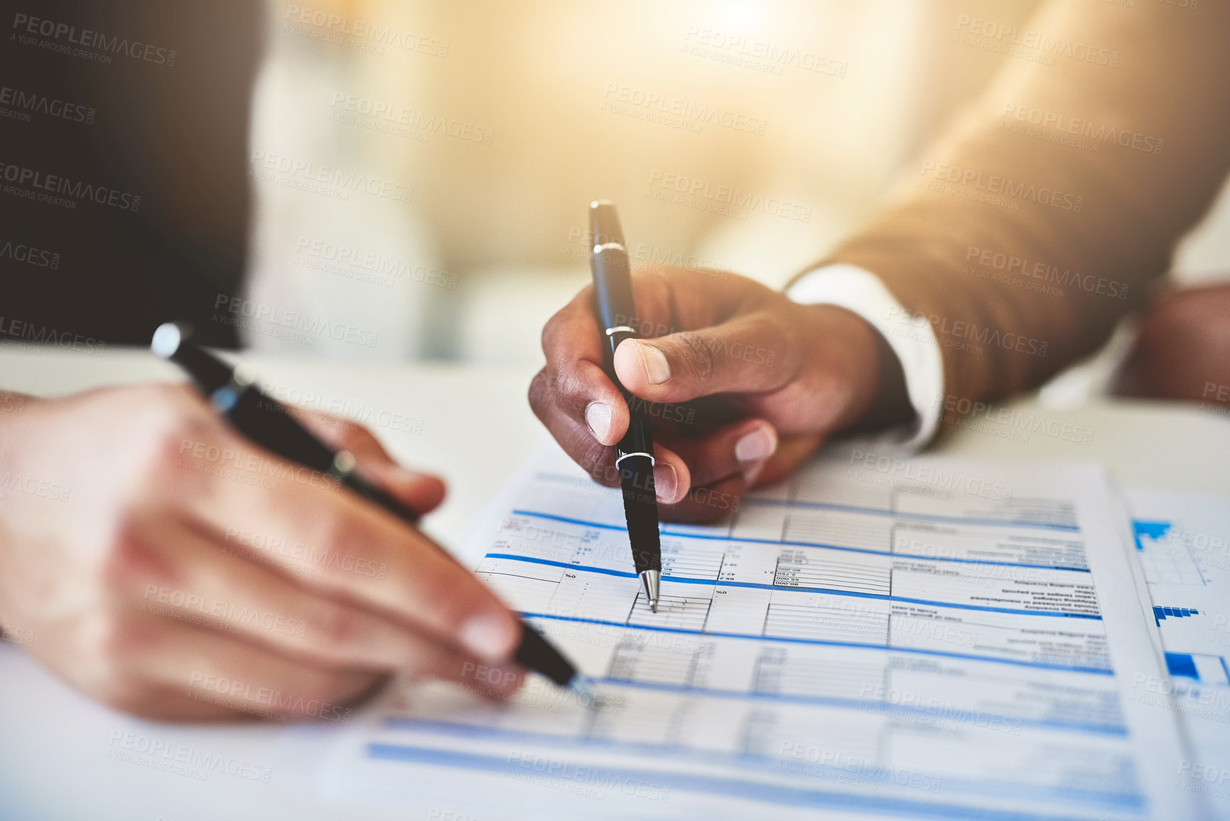 Buy stock photo Closeup shot of two unidentifiable businesspeople going through some paperwork in an office