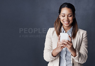 Buy stock photo Studio shot of a young businesswoman using her cellphone against a grey background