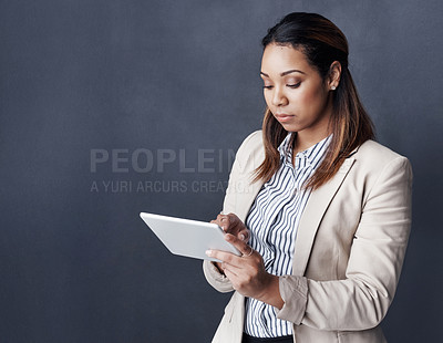 Buy stock photo Studio shot of a young businesswoman using her tablet against a grey background