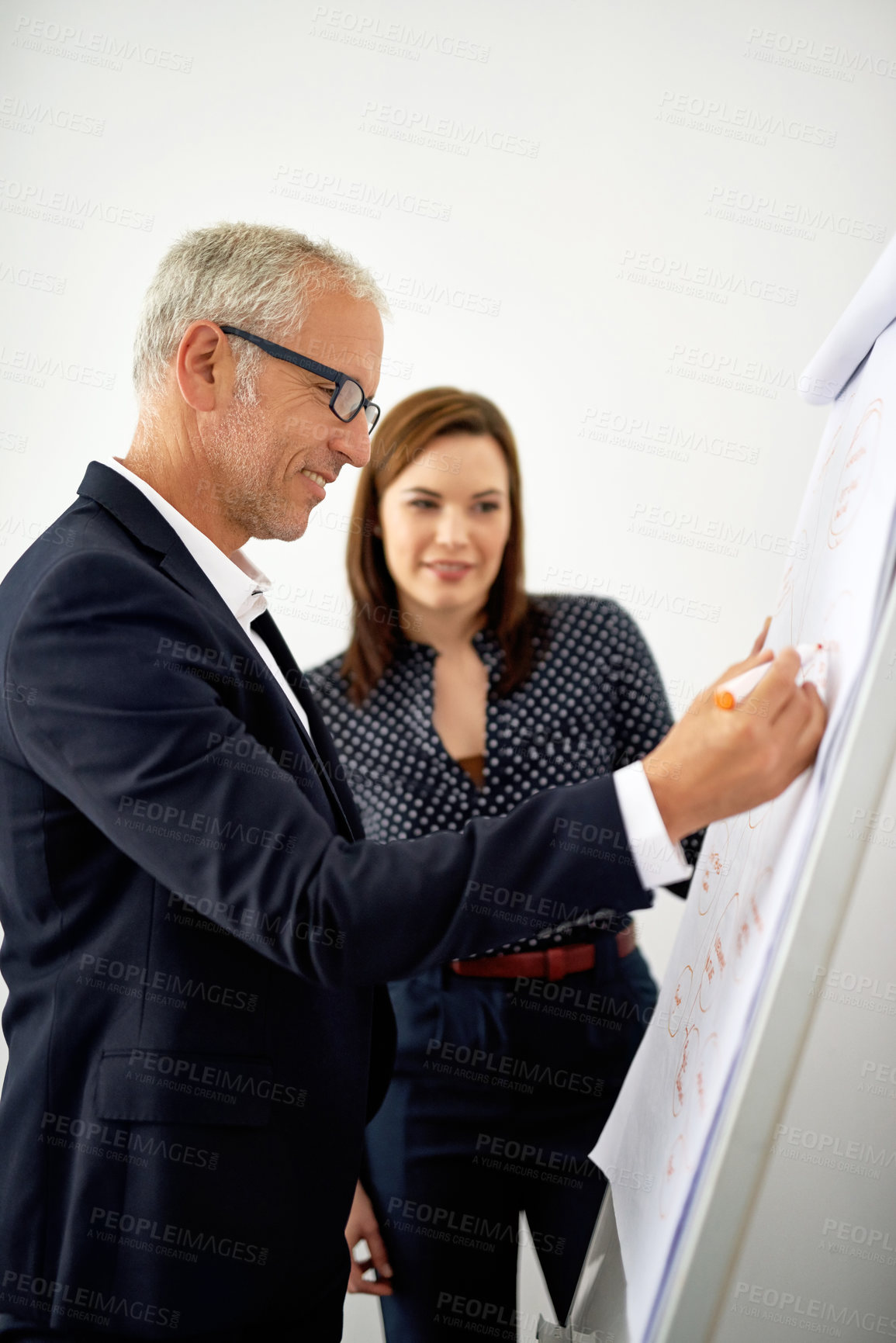 Buy stock photo Cropped shot of two colleagues brainstorming on a whiteboard in an office