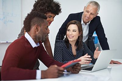 Buy stock photo Cropped shot of a group of businesspeople discussing work over a laptop