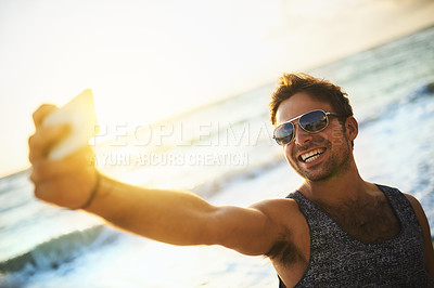 Buy stock photo Cropped shot of a young man taking a selfie at the beach