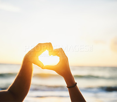 Buy stock photo Cropped shot of a couple forming a heart shape with their hands at the beach