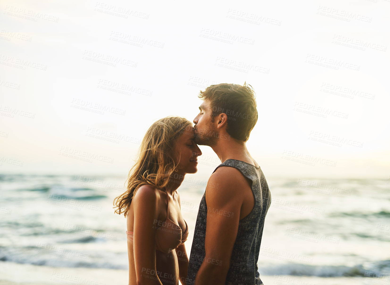 Buy stock photo Man, woman and forehead kiss at beach for love, travel and vacation in nature for summer sunset. Happy, couple and holiday with sunshine, smile and people together for date on island in Thailand