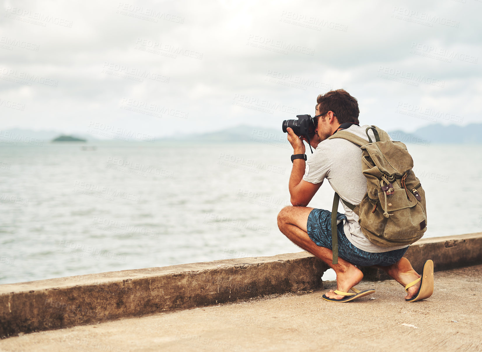 Buy stock photo Man, camera and photography by sea as travel journalist for picture memory for creative, digital or lens. Male person, equipment and shoot in Thailand for nature trip as photographer, view or artist