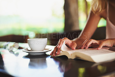 Buy stock photo Cropped shot of an unidentifiable woman reading a book in a cafe