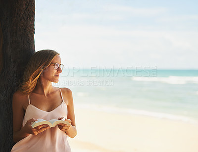Buy stock photo Cropped shot of a young woman reading a book at the beach