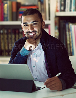 Buy stock photo Portrait of a focused young man working on a digital tablet in his home office in the early evening