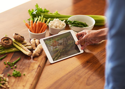 Buy stock photo Cropped shot of a man using a digital tablet while preparing a healthy meal at home