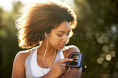 Buy stock photo Shot of an attractive young woman listening to music while exercising outdoors