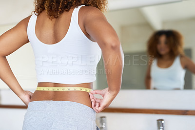 Buy stock photo Cropped shot of a young woman measuring her waist in the bathroom