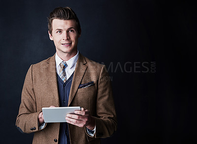 Buy stock photo Studio shot of a young businessman using his tablet against a dark background
