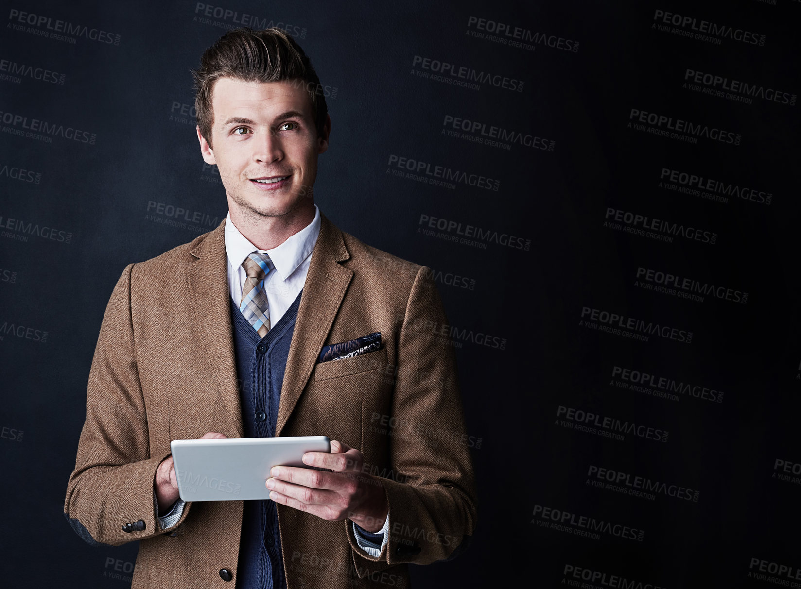 Buy stock photo Studio shot of a young businessman using his tablet against a dark background