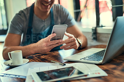 Buy stock photo Cropped shot of an unrecognizable man using on his cellphone in his coffee shop