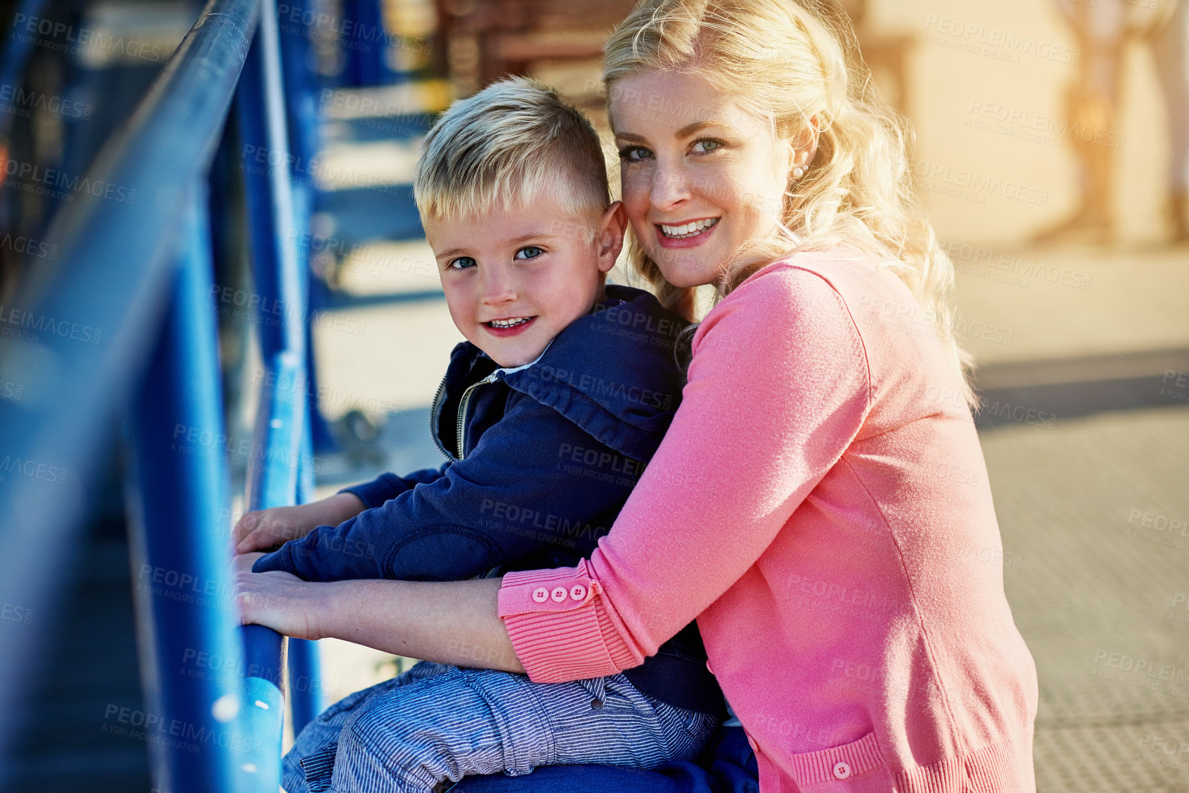 Buy stock photo Portrait of a mother posing with her little boy on her lap while enjoying a day outside