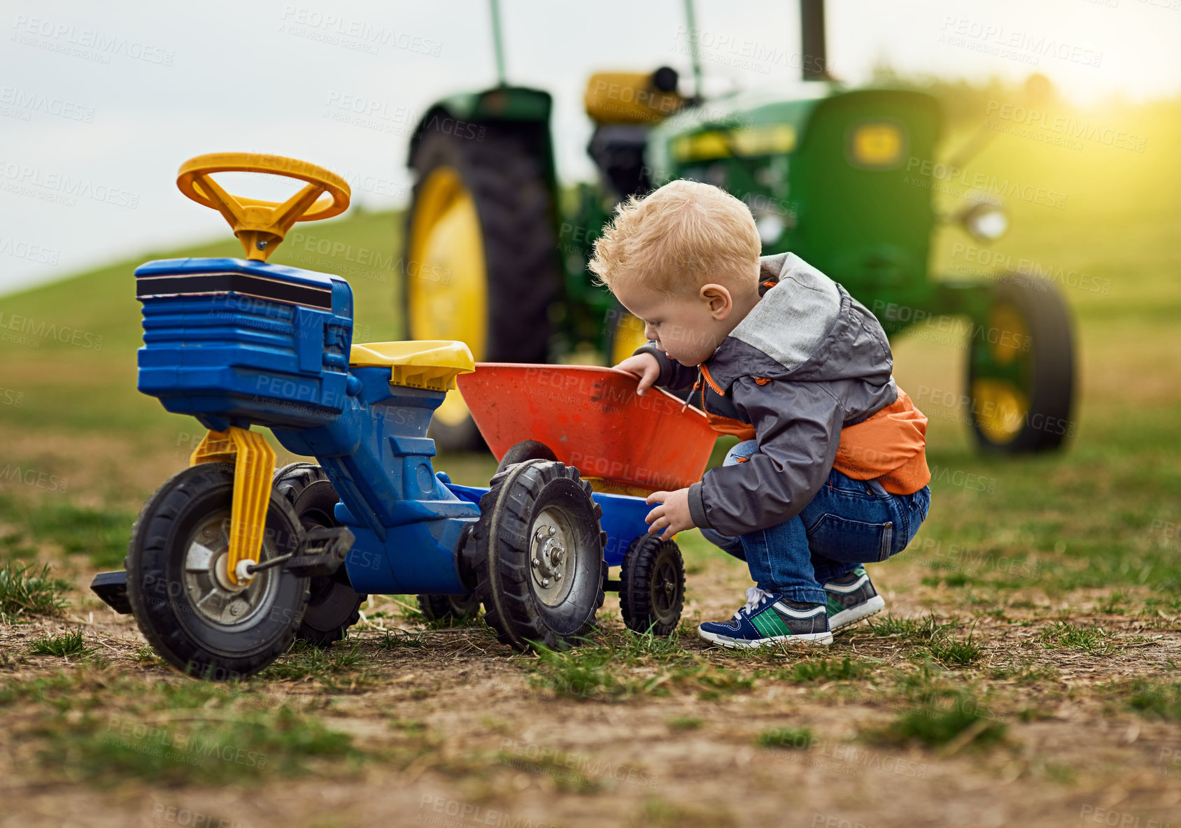 Buy stock photo Kid, bike and child with development in countryside for eco, farming and toys on lawn. Tractor, young boy and outdoor for summer holiday, growth and learning in nature with truck for motor skills