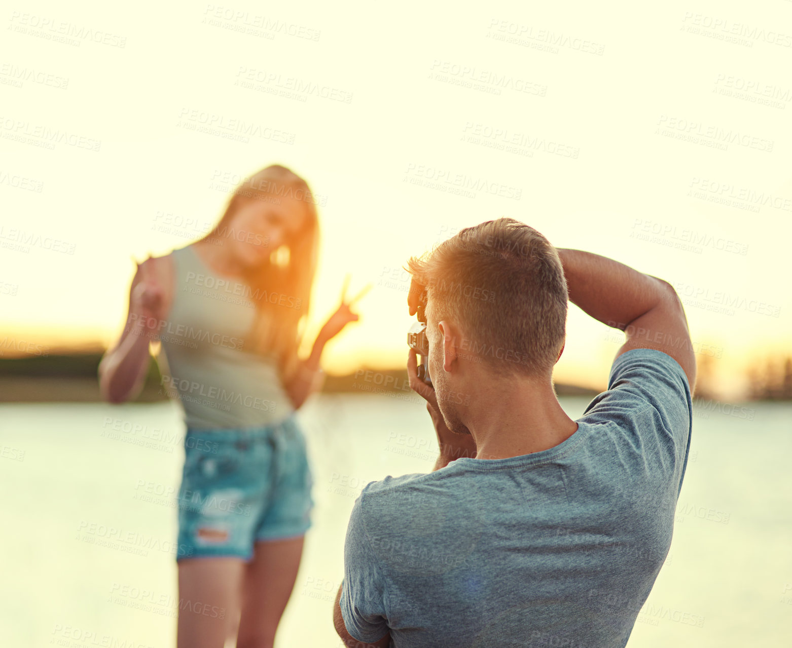 Buy stock photo Cropped shot of a young man taking a photo of his girlfriend outside