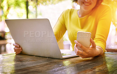 Buy stock photo Cropped shot of an unrecognizable young woman using her laptop outside