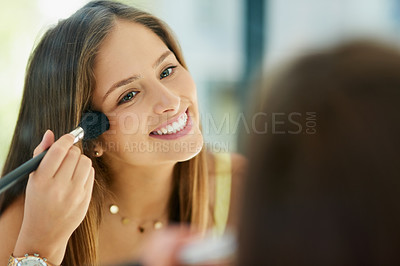 Buy stock photo Shot of an attractive young woman applying makeup to her face with a brush