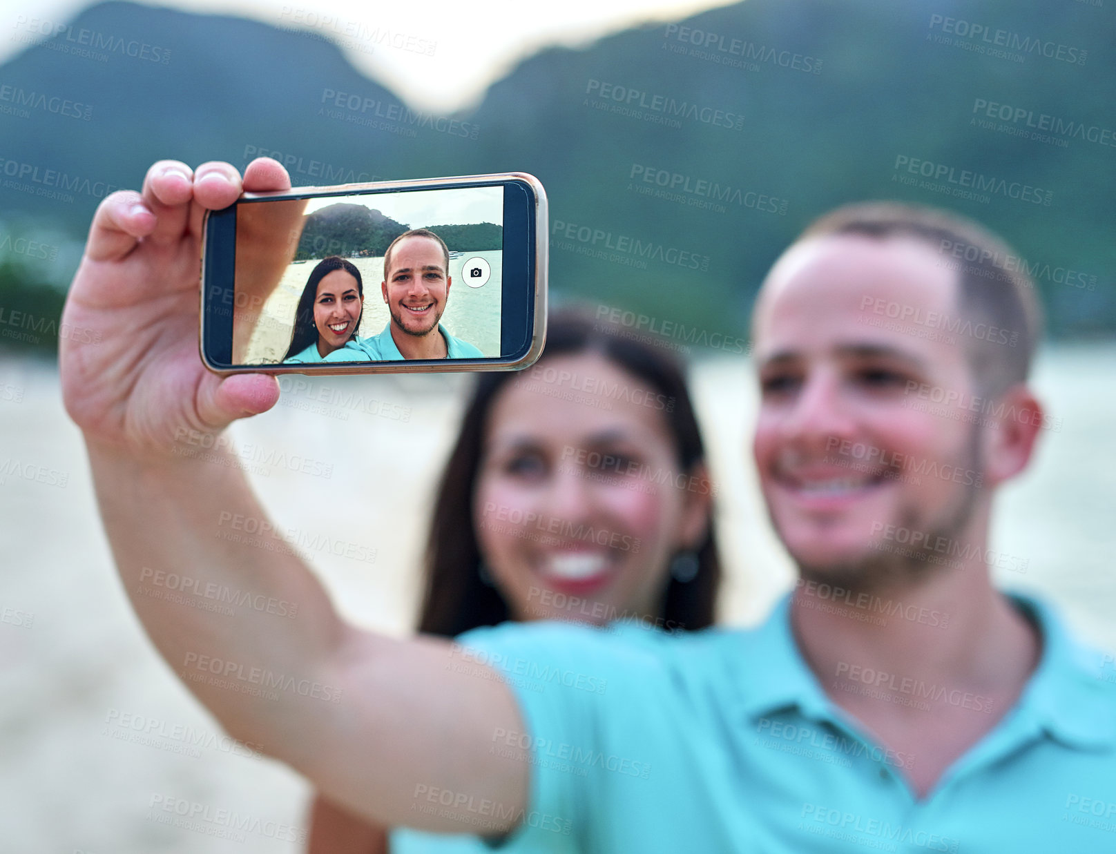 Buy stock photo Couple, phone and selfie at beach for social media, memory and travel with love by ocean. Man, woman and smartphone by sea outdoor for post, date and happiness with smile by water in Greece together