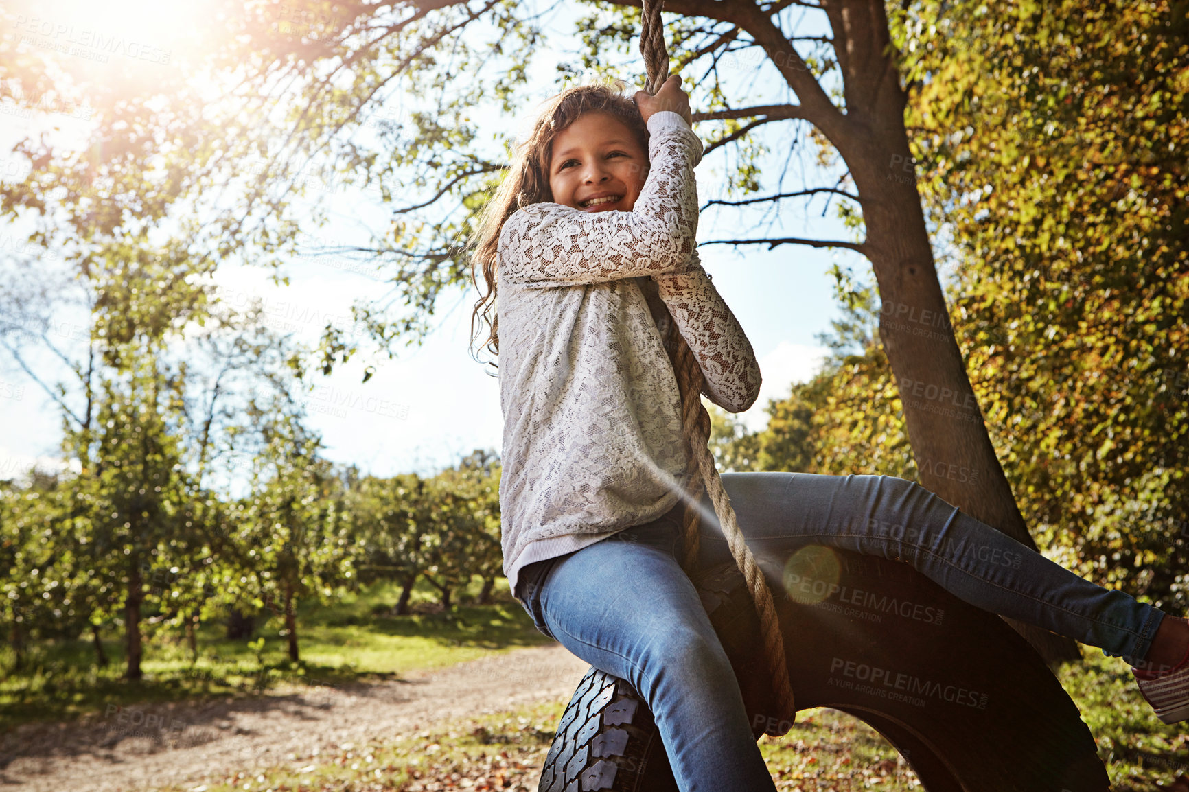 Buy stock photo Portrait of a happy little girl swinging on a tyre in a garden