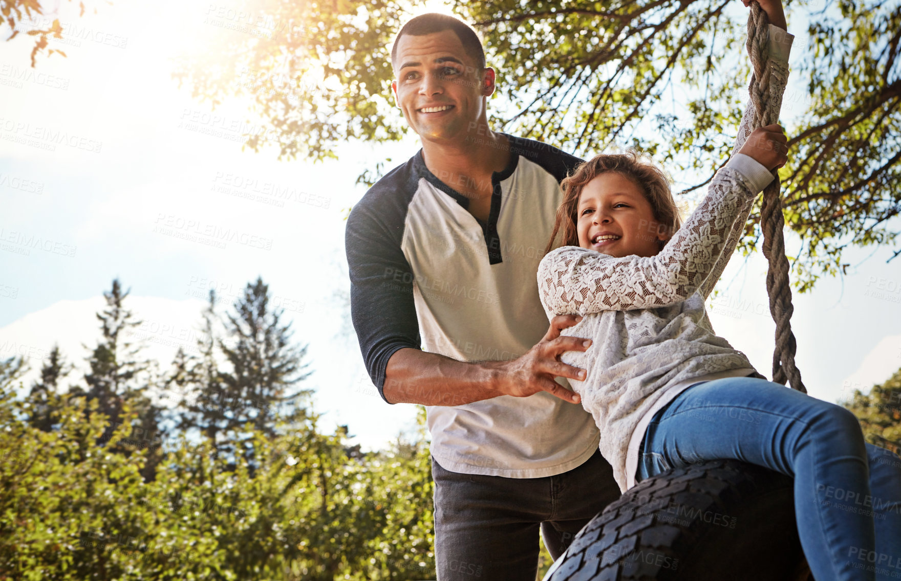 Buy stock photo Shot of a happy father pushing his daughter on a tyre swing