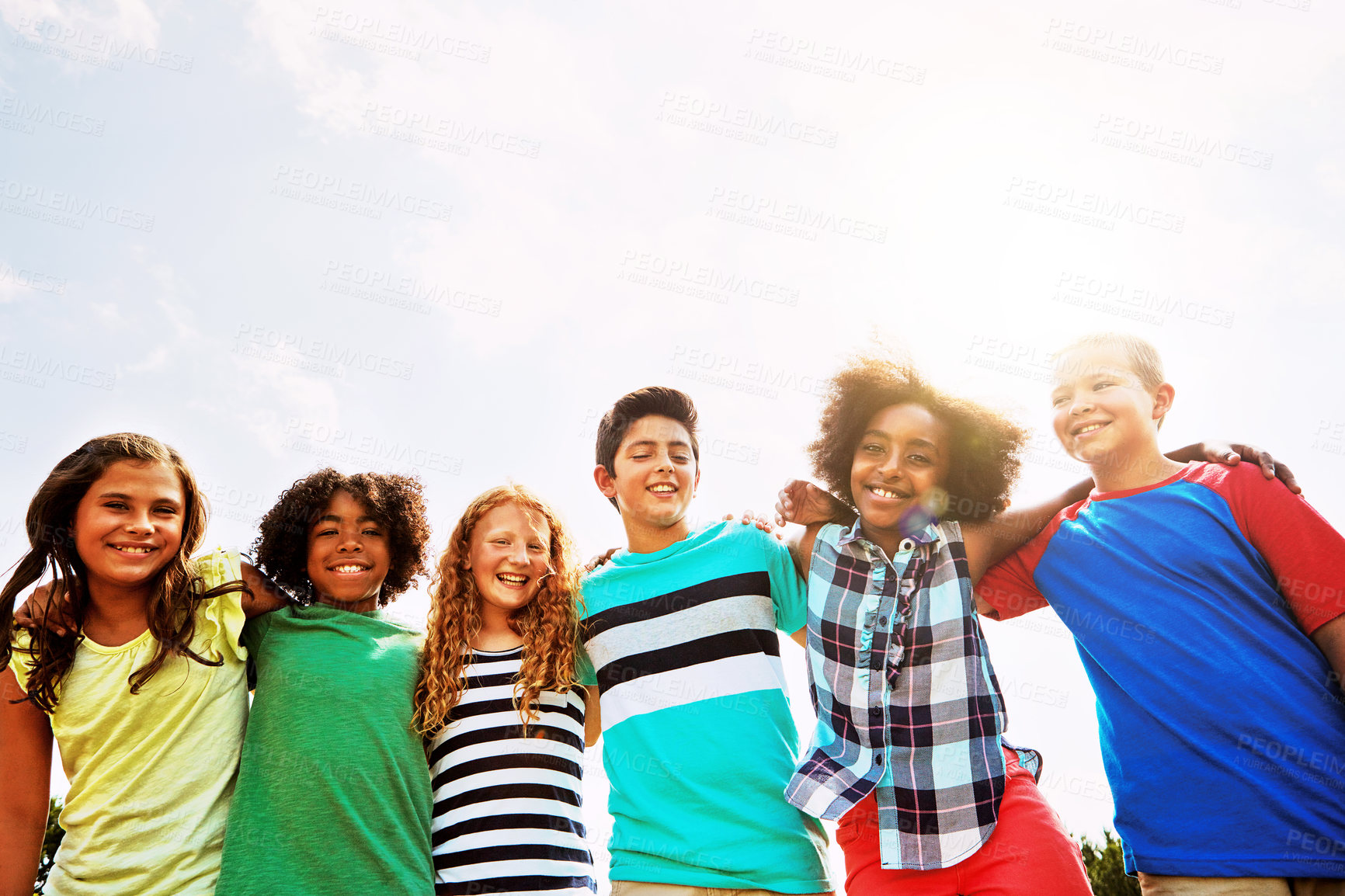 Buy stock photo Portrait of a group of diverse and happy kids hanging out together on a bright day outside