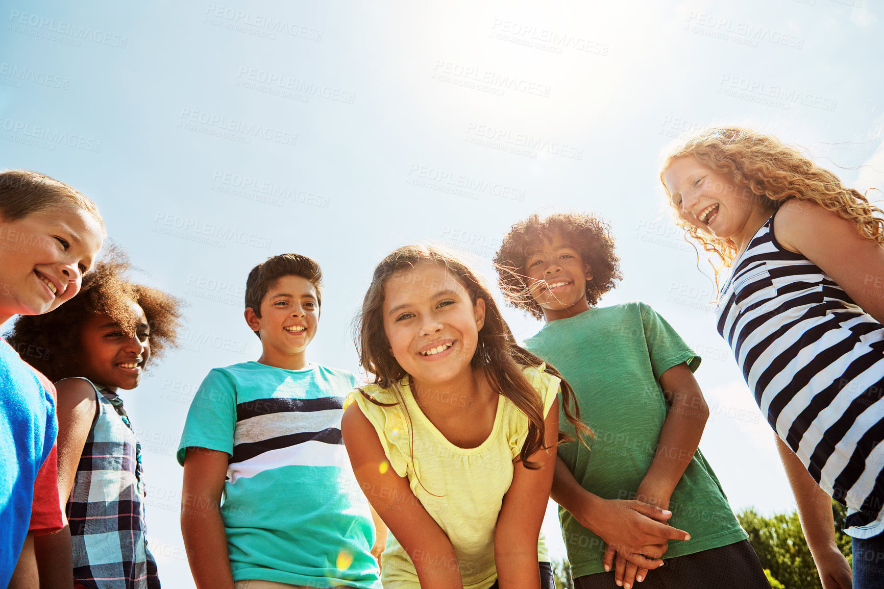 Buy stock photo Portrait of a group of diverse and happy kids hanging out together on a bright day outside