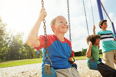 Buy stock photo Cropped shot of young boys playing on the swings at the park