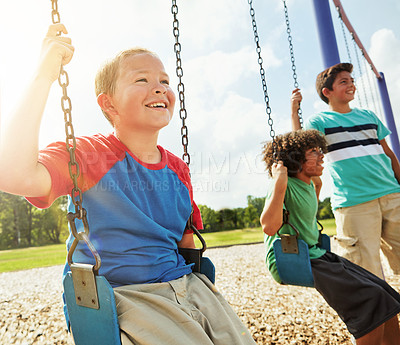 Buy stock photo Cropped shot of young boys playing on the swings at the park