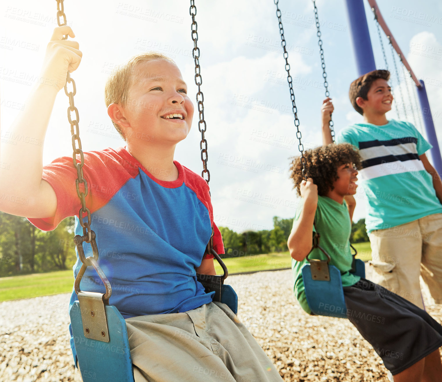 Buy stock photo Cropped shot of young boys playing on the swings at the park