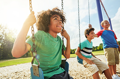 Buy stock photo Cropped shot of young boys playing on the swings at the park