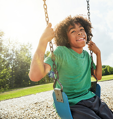 Buy stock photo Cropped shot of a young boy playing on a swing at the park