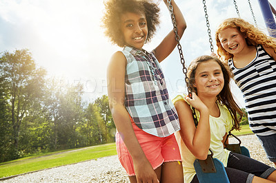 Buy stock photo Portrait of young girls playing on the swings at the park