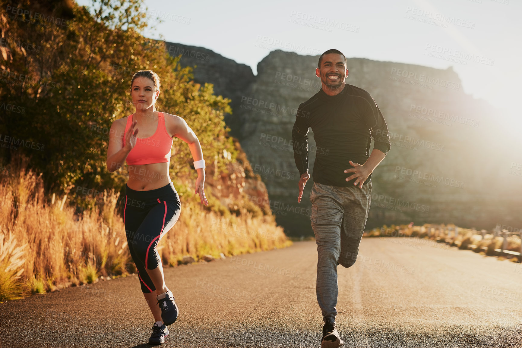 Buy stock photo Couple, running and fitness on road by mountain with smile for speed, development and progress in morning. Man, woman and happy with diversity for training, exercise or workout for wellness in nature