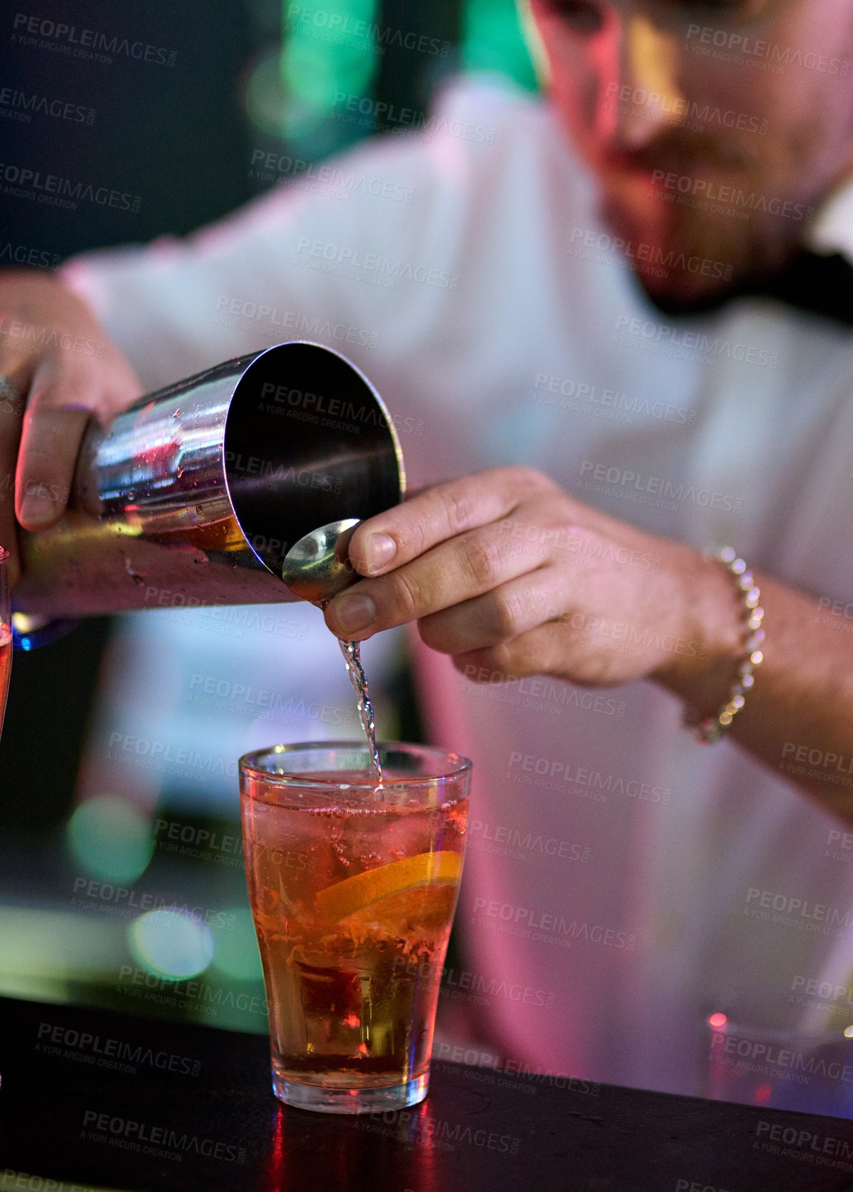 Buy stock photo Cropped shot of a barman mixing drinks in a nightclub