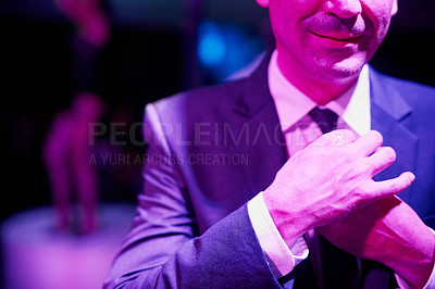 Buy stock photo Shot of a seedy businessman adjusting his tie in a go go bar with a woman dancing on a pole behind him