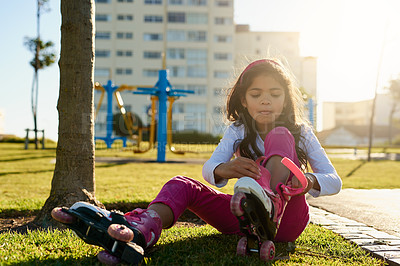 Buy stock photo Shot of a young girl putting on her roller skates at the park