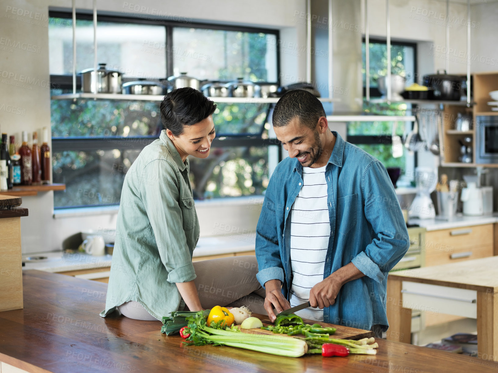 Buy stock photo Shot of a smiling young couple preparing a meal together in their kitchen