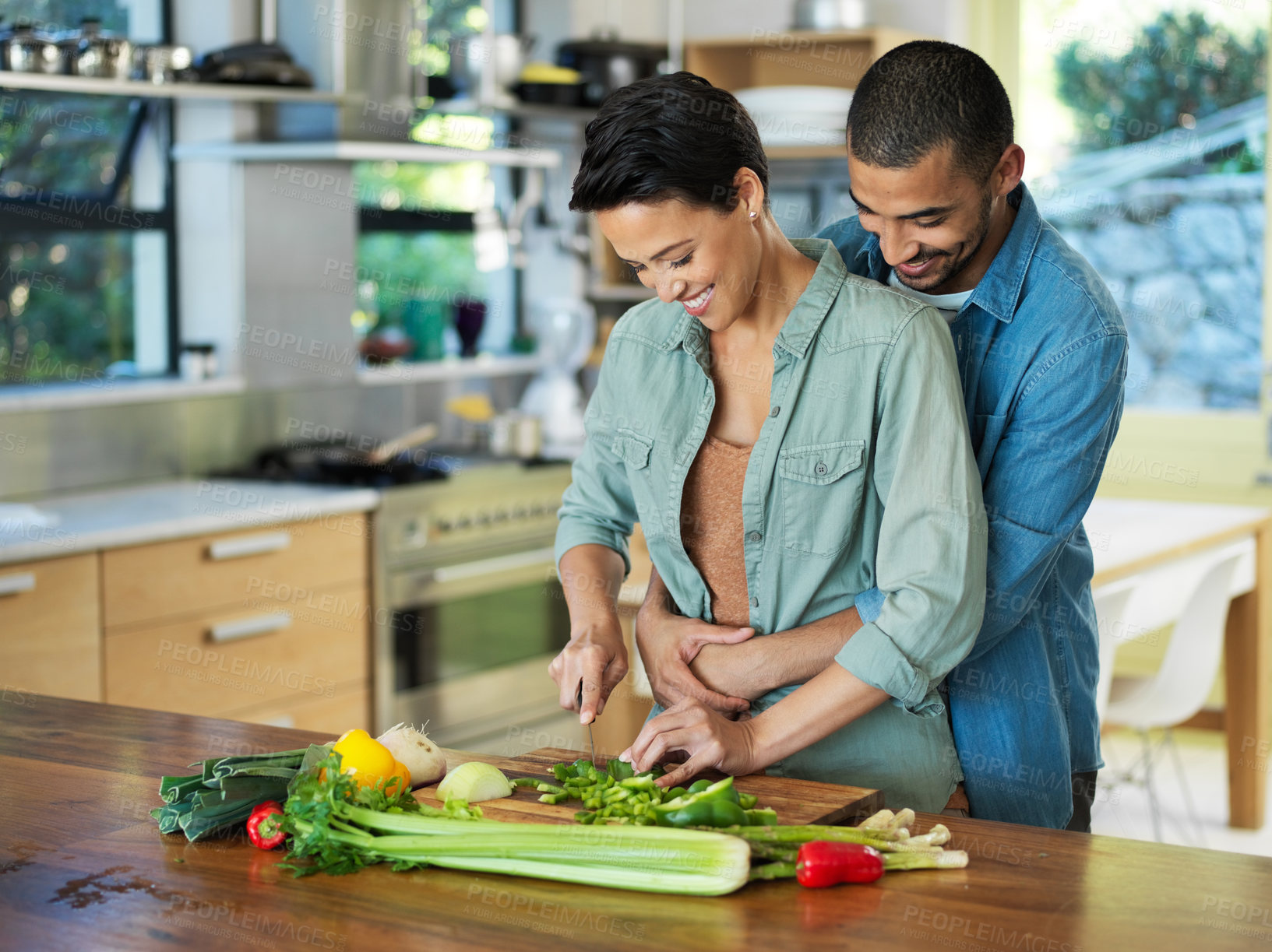 Buy stock photo Cooking, vegetables and couple hug in kitchen for love, healthy food and bonding together with evening date. Smile, happy man and woman with knife for cutting, nutrition meal or preparation in home