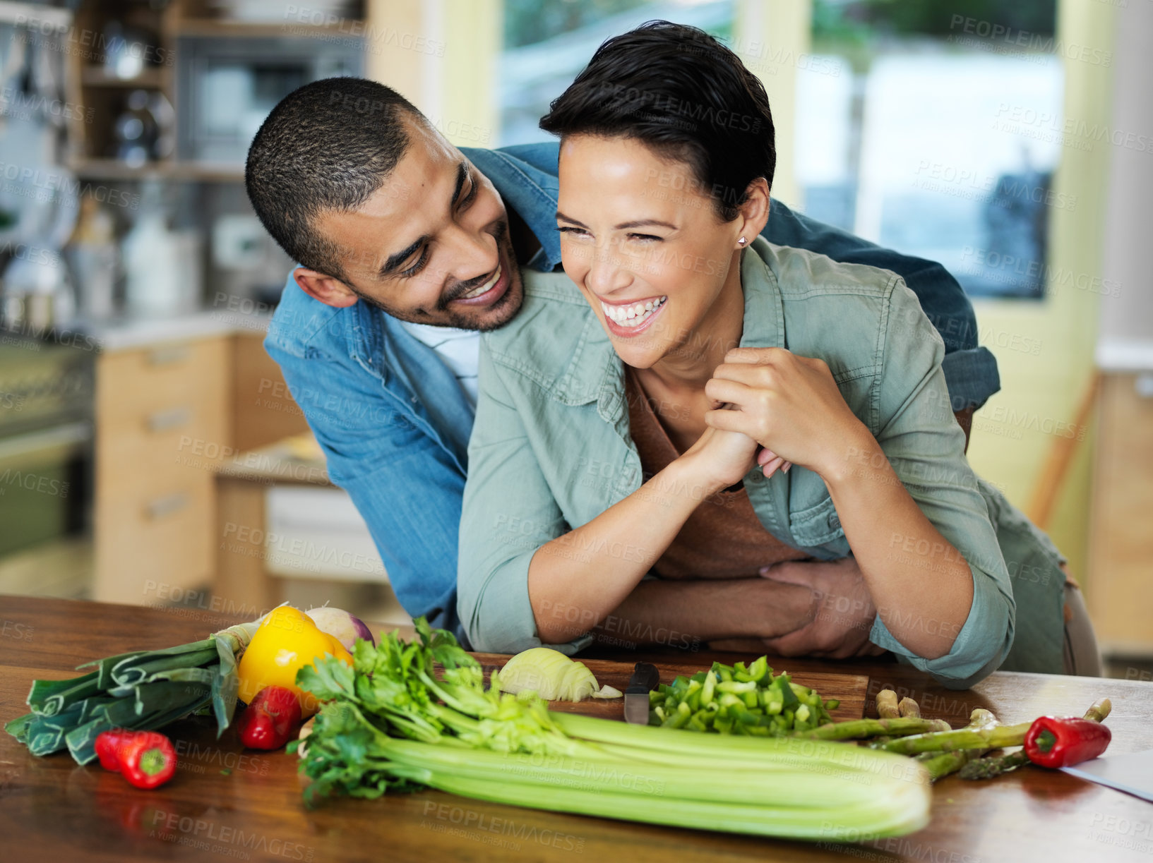 Buy stock photo Cooking, smile and couple embrace at kitchen counter for preparation, healthy food and bonding together on date. Vegetables, happy man and vegan woman for dinner, nutrition meal or love in home