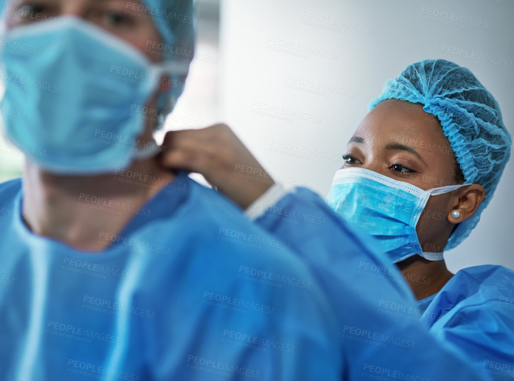 Buy stock photo Shot of surgeons putting on protective clothing in preparation for a surgery