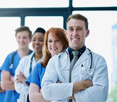 Buy stock photo Portrait of a team of confident young doctors standing in a line