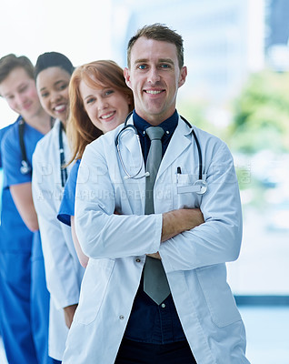 Buy stock photo Portrait of a team of confident young doctors standing in a line