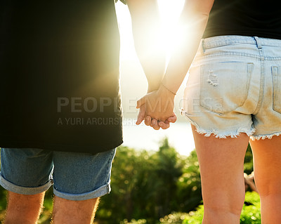 Buy stock photo Rearview shot of an unrecognizable young couple standing hand in hand outside