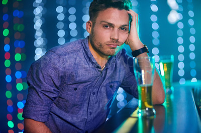 Buy stock photo Portrait of a young man looking upset while sitting at the bar in a club